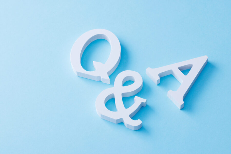 水色の背景に置かれた、白く立体的な「Q & A」の文字。質問と回答（FAQ）や問題解決の概念を表している。